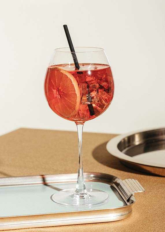 Close-up of Aperol Spritz in wine glass with orange slice-12