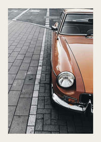 Närbild av orange klassisk bil parkerad på gatsten-3