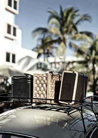 Photographic view of old suitcases on car under palm trees-7