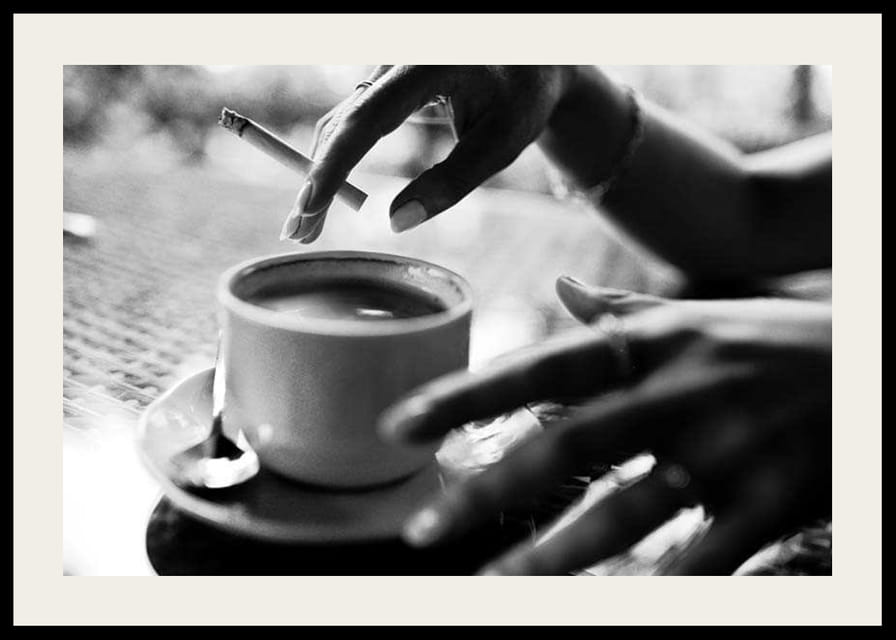 Czarno-białe zdjęcie ręki z papierosem nad filiżanką kawy-12