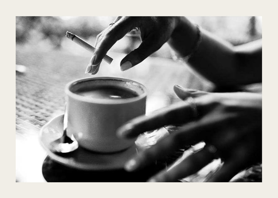 Czarno-białe zdjęcie ręki z papierosem nad filiżanką kawy-12