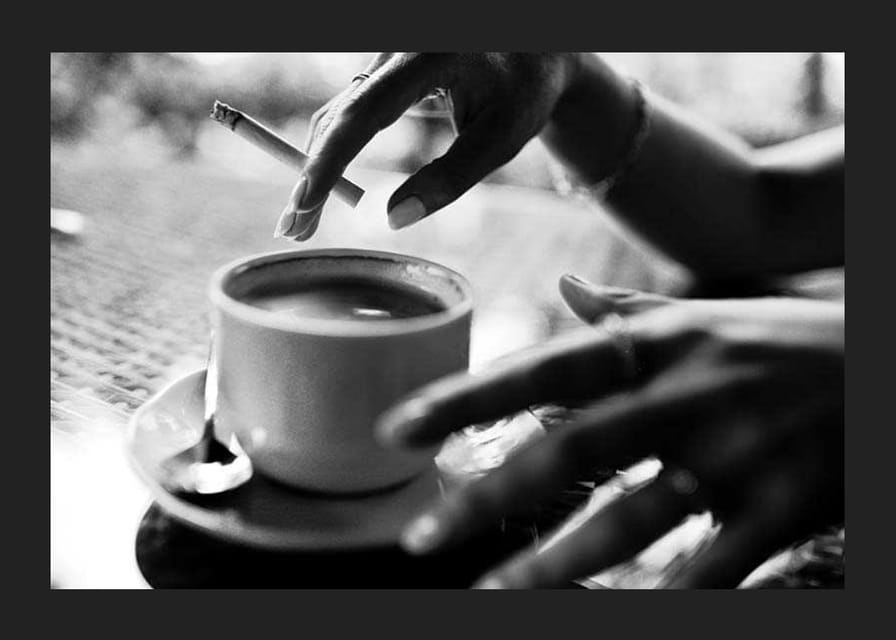 Czarno-białe zdjęcie ręki z papierosem nad filiżanką kawy-12