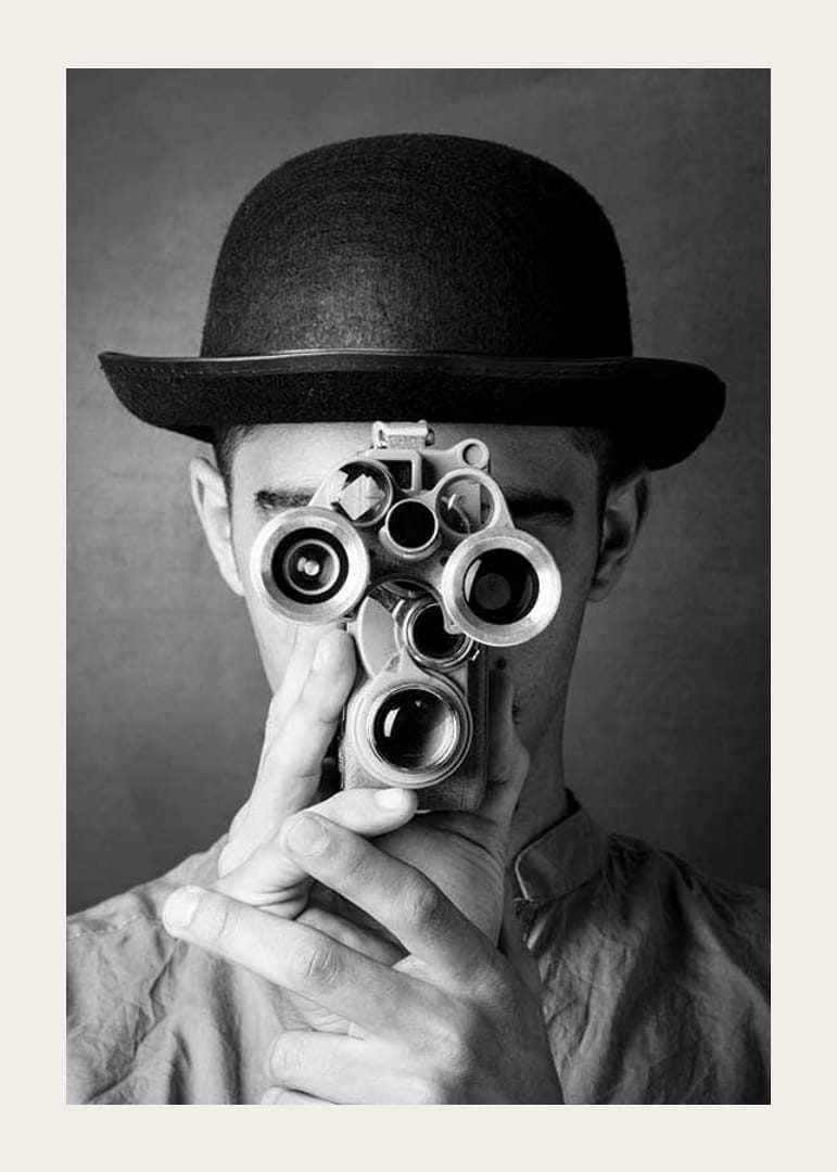 Primer plano en blanco y negro de un joven con sombrero y una cámara de película antigua-12