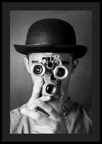 Primer plano en blanco y negro de un joven con sombrero y una cámara de película antigua-4