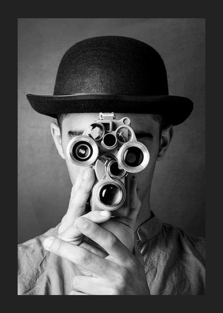 Primer plano en blanco y negro de un joven con sombrero y una cámara de película antigua-12