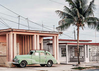 Fotografi av grön vintagebil framför pastellfärgat hus och palm-7