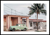 Fotografi av grön vintagebil framför pastellfärgat hus och palm-0
