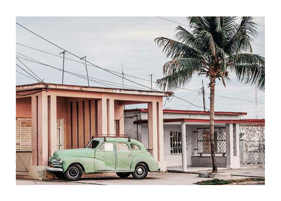 Fotografi av grön vintagebil framför pastellfärgat hus och palm-12