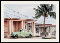 Fotografi av grön vintagebil framför pastellfärgat hus och palm-2
