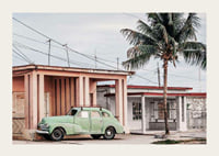 Fotografi av grön vintagebil framför pastellfärgat hus och palm-3