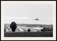 Black and white photograph of airplane landing on long runway-2
