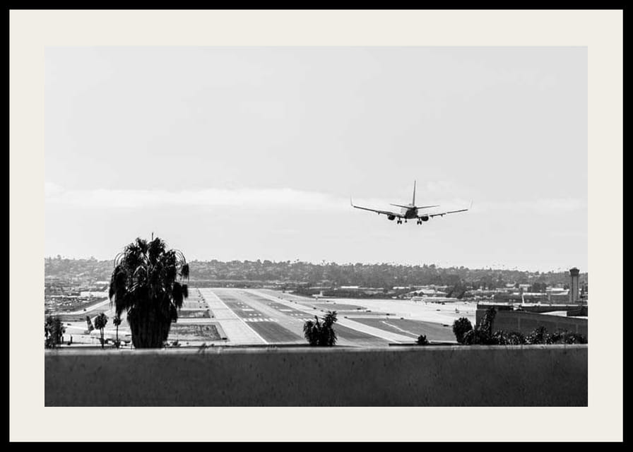 Black and white photograph of airplane landing on long runway-12