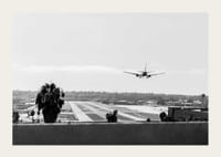 Black and white photograph of airplane landing on long runway-3
