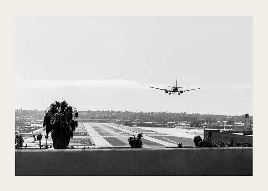 Black and white photograph of airplane landing on long runway-12