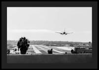 Black and white photograph of airplane landing on long runway-4