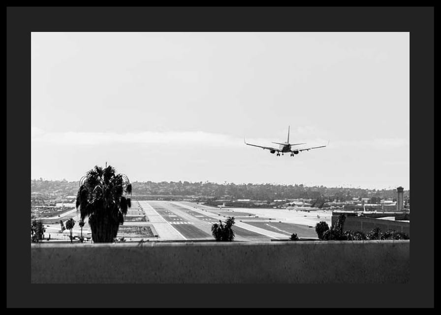 Black and white photograph of airplane landing on long runway-12
