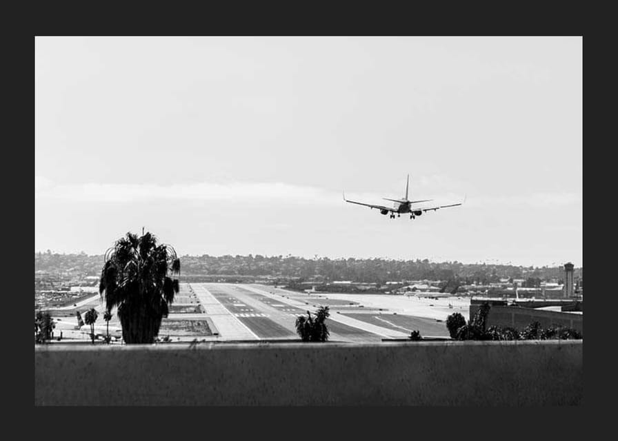 Black and white photograph of airplane landing on long runway-12