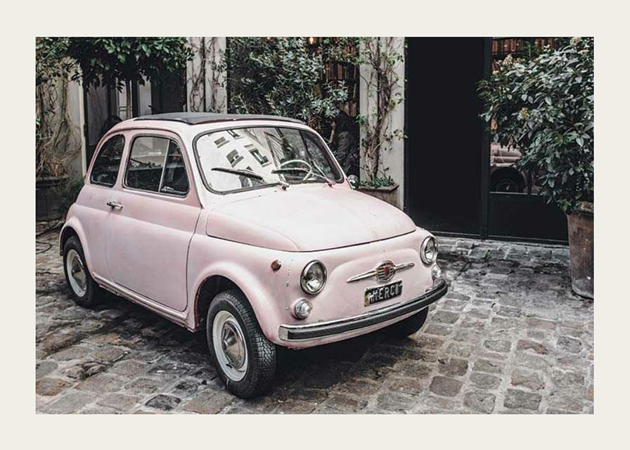 Vintage rosa bil parkerad på kullerstensgata utomhus-12