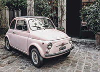 Vintage rosa bil parkerad på kullerstensgata utomhus-7