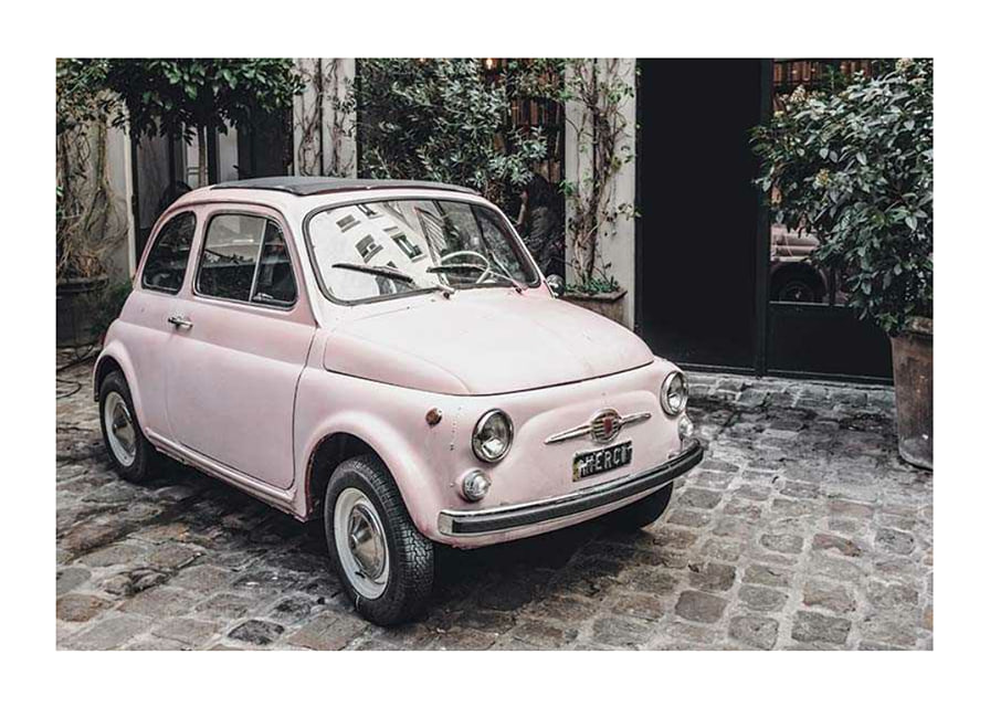 Vintage rosa bil parkerad på kullerstensgata utomhus-12
