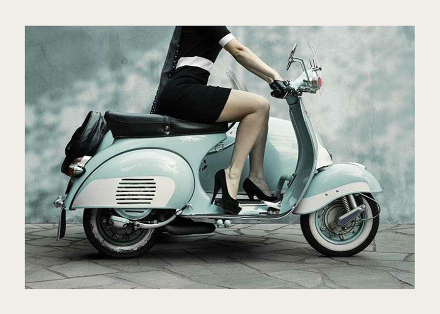 Photograph of woman on light blue retro scooter against gray wall-12