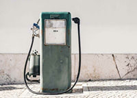 Fotografia de uma bomba de gasolina vintage verde contra uma parede clara-7