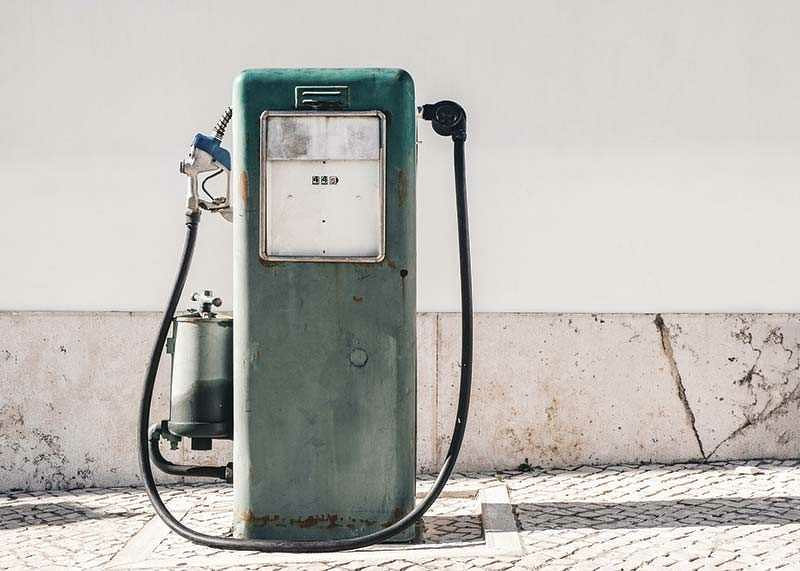 Fotografia de uma bomba de gasolina vintage verde contra uma parede clara-12