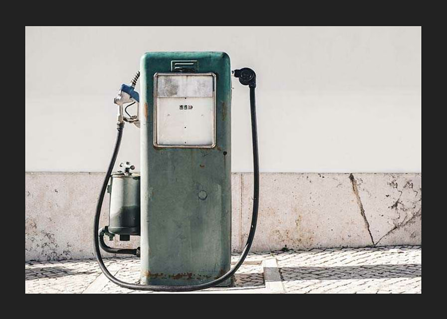 Fotografia de uma bomba de gasolina vintage verde contra uma parede clara-12
