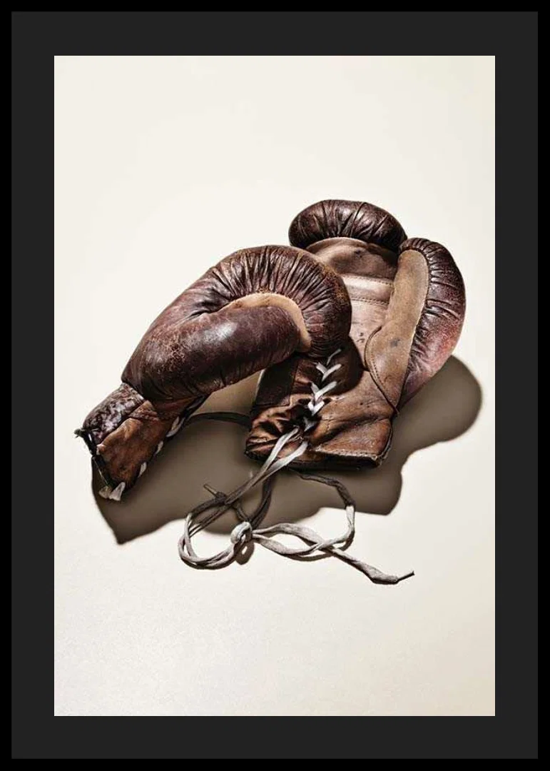 Photograph of worn brown boxing gloves on light background-12