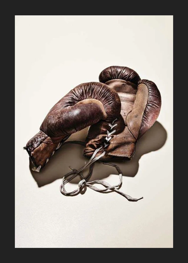 Photograph of worn brown boxing gloves on light background-12