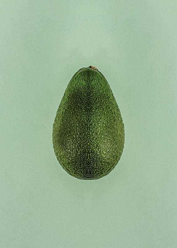 Photograph of whole green avocado against a solid green background-12