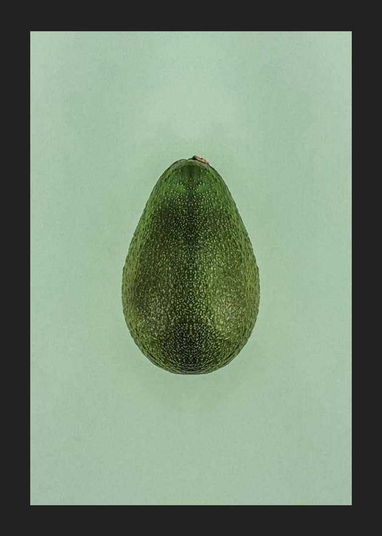 Photograph of whole green avocado against a solid green background-12