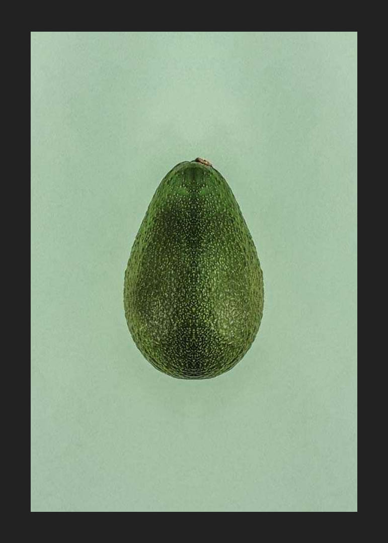 Foto van een hele groene avocado tegen een effen groene achtergrond-12