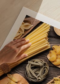Verschiedene Arten von ungekochten Nudeln auf Holzplatte vor dunklem Untergrund-9