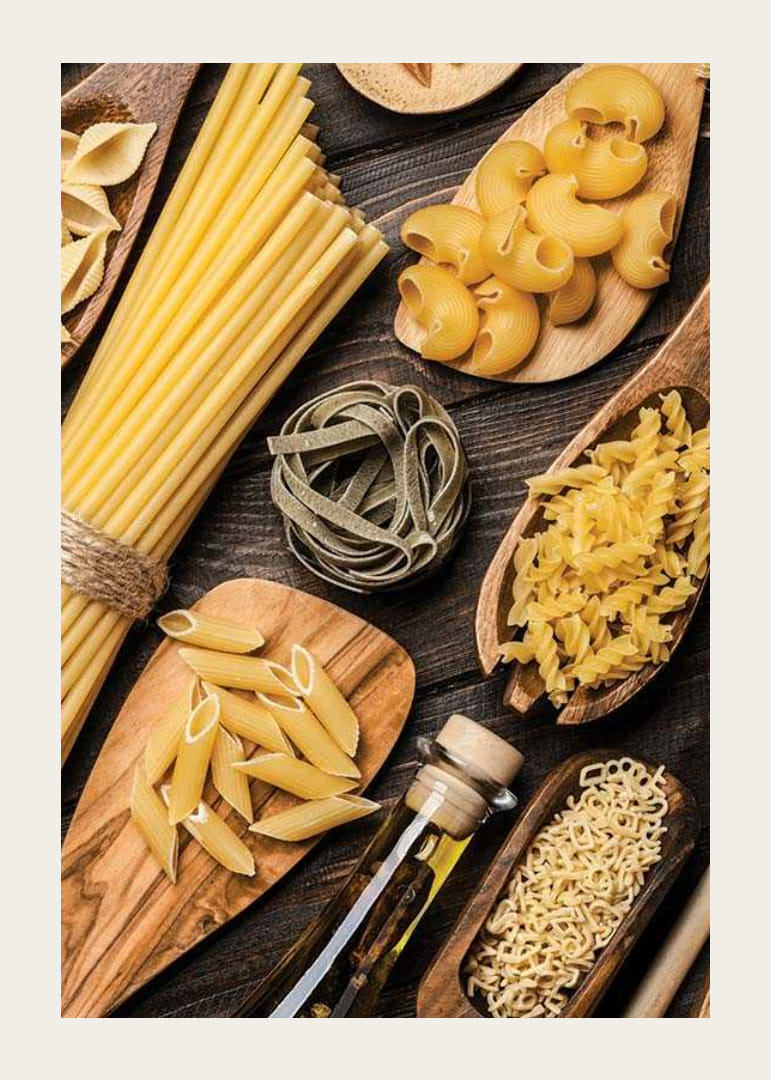 Flera sorters okokt pasta på träfat mot mörk yta-12