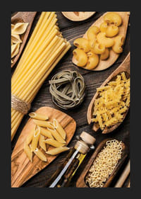 Flera sorters okokt pasta på träfat mot mörk yta-5