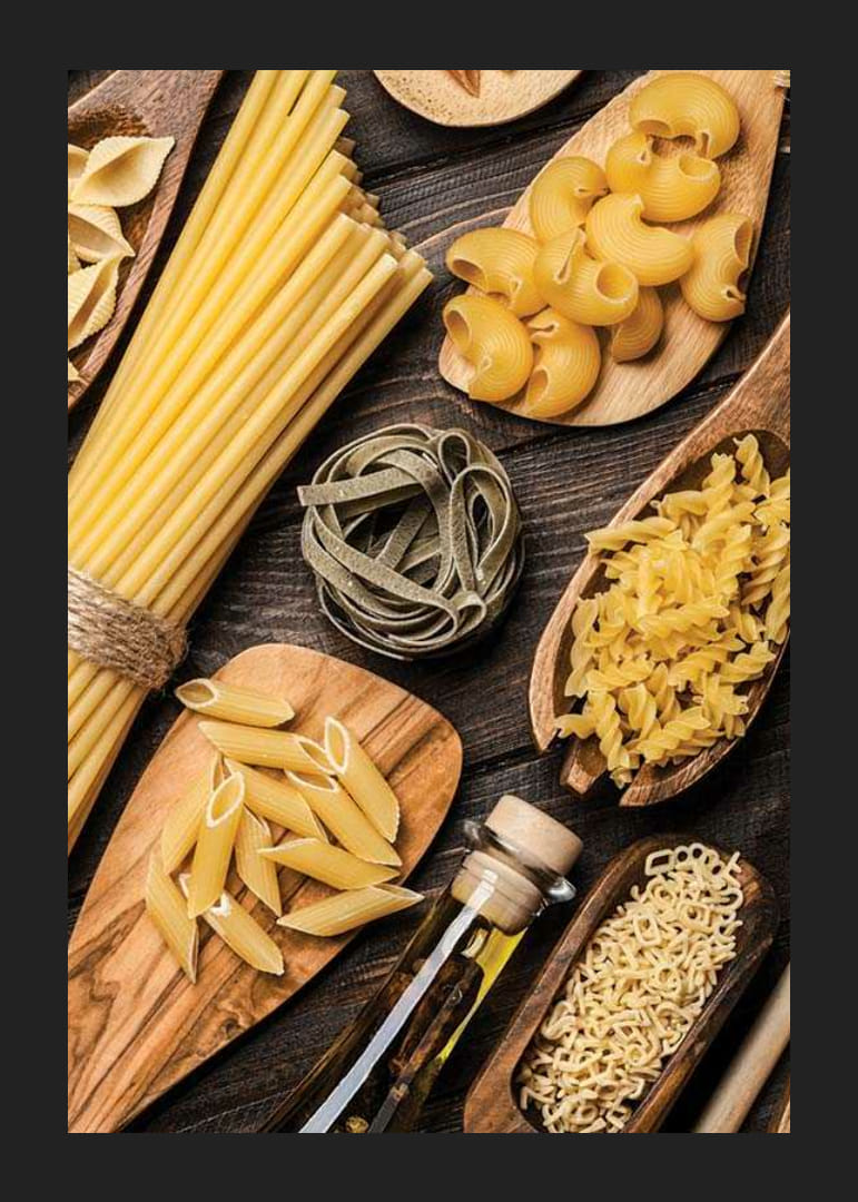 Flera sorters okokt pasta på träfat mot mörk yta-12