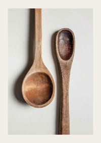 Two wooden spoons in close-up against light gray background, photographic-3