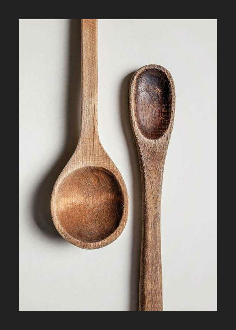 Two wooden spoons in close-up against light gray background, photographic-12