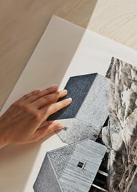 Valokuva kahdesta harmaasta puurakennuksesta kallioiden ja veden äärellä-9