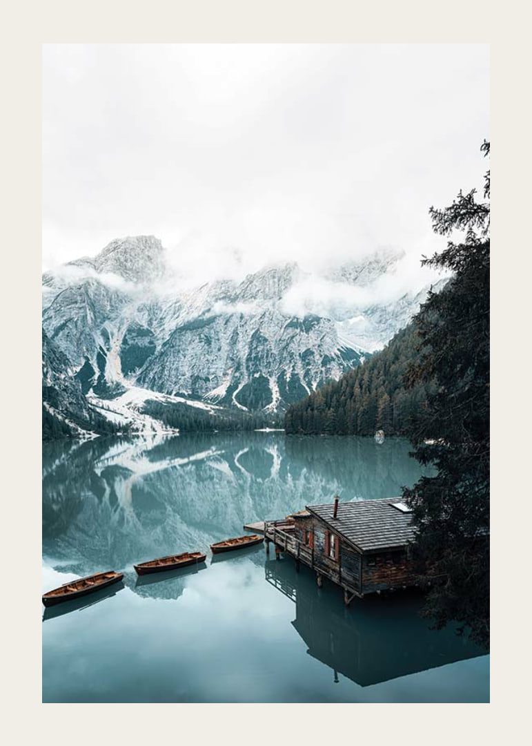 Photograph of snow-capped mountains, wooden pier and rowboats on a mirror-like lake-12