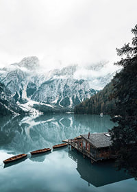 Photograph of snow-capped mountains, wooden pier and rowboats on a mirror-like lake-7