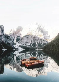 Photograph of rowboats on mirror-like lake, snow-capped mountains-7