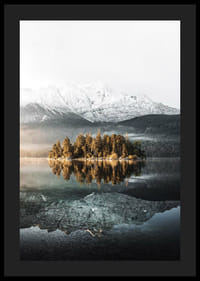 Fotografia di una piccola isola boscosa in un lago limpido con montagne innevate-4