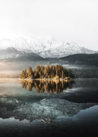 Fotografía de una pequeña isla boscosa en un lago cristalino con montañas cubiertas de nieve.-7