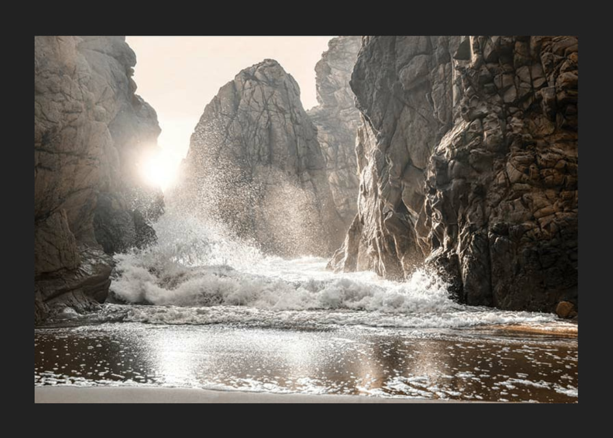 Photograph of waves crashing against rocks in soft backlight-12