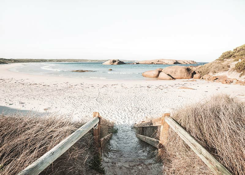 Fotografi av trappa ner till ljus sandstrand med hav och klippor-12