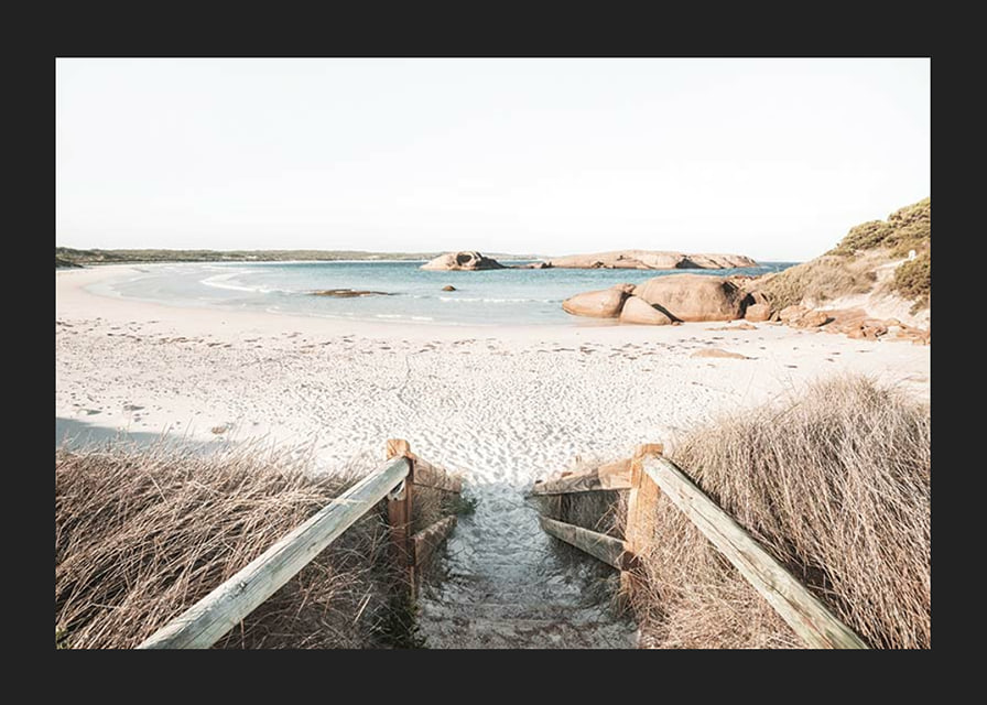 Fotografi av trappa ner till ljus sandstrand med hav och klippor-12