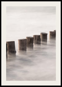 Fotografia di pali di legno in linea retta circondati dalla superficie nebbiosa del mare-2