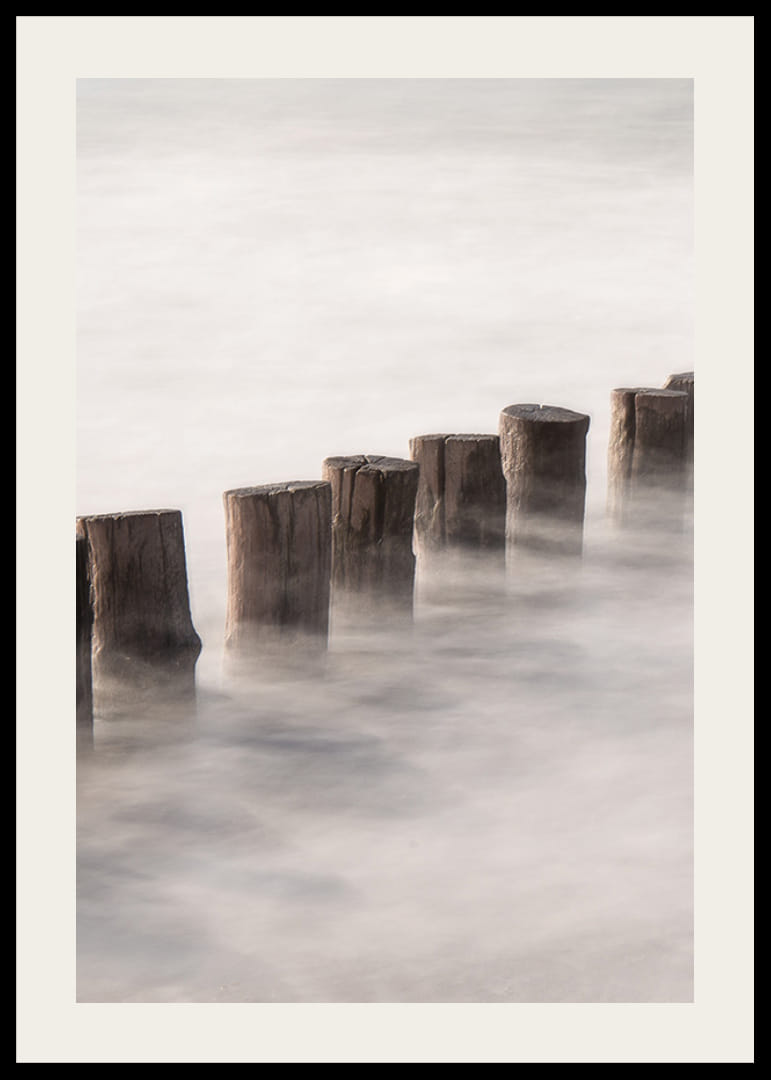 Fotografia di pali di legno in linea retta circondati dalla superficie nebbiosa del mare-12